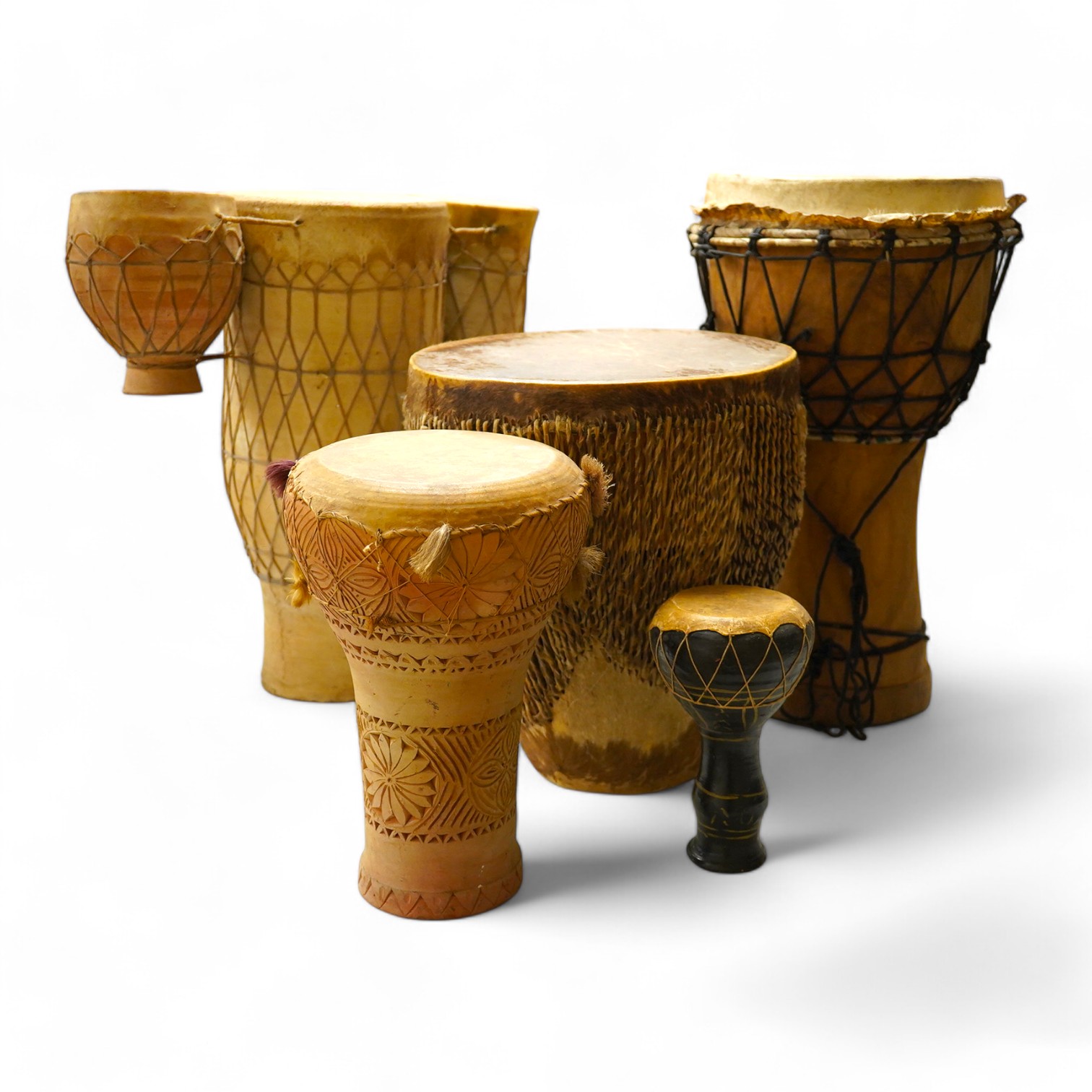 Five African drums; a Djembe, 50cm high, together with four others, including a pottery triple drum, etc. Condition - fair to good.